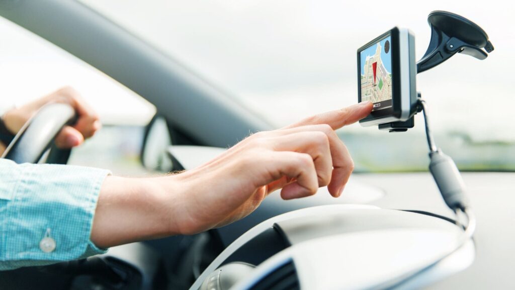 Kuljettaja käyttää GPS-navigaattoria autossa ajon aikana.